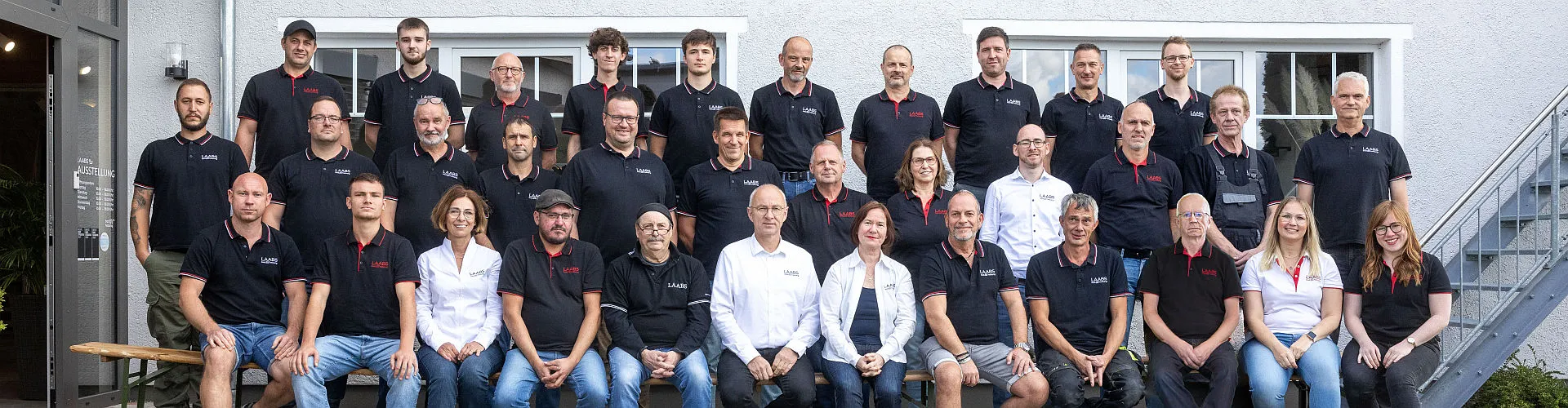Das gesamte Team des SHK-Unternehmens LAABS posiert gemeinsam für ein Teamfoto vor dem Firmengebäude. 