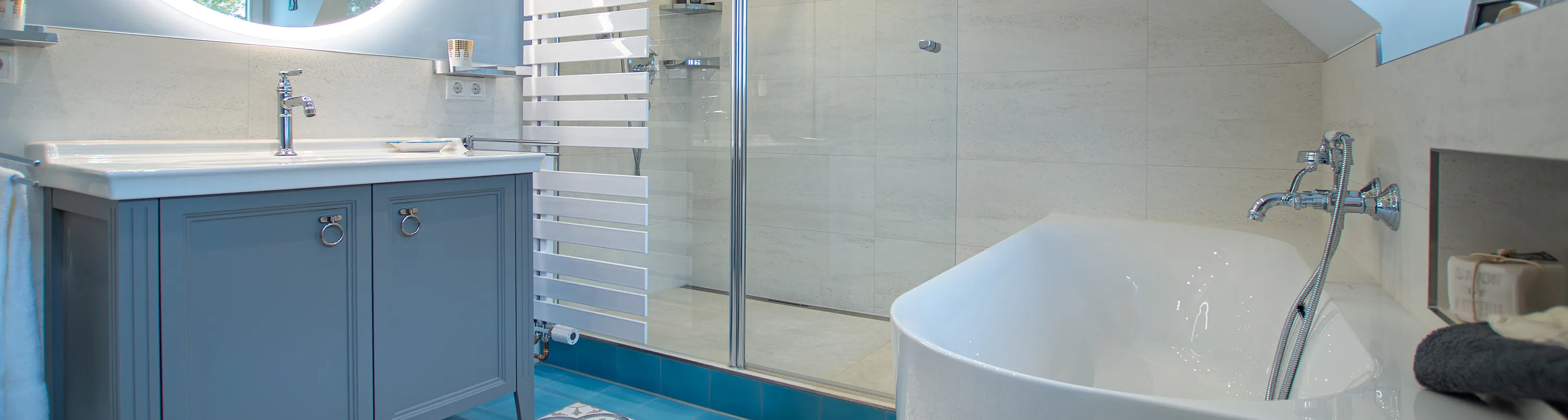 Badezimmer im Blautönen im Landhausstil, im Mittelpunkt steht ein blaugrauer Waschtisch. 