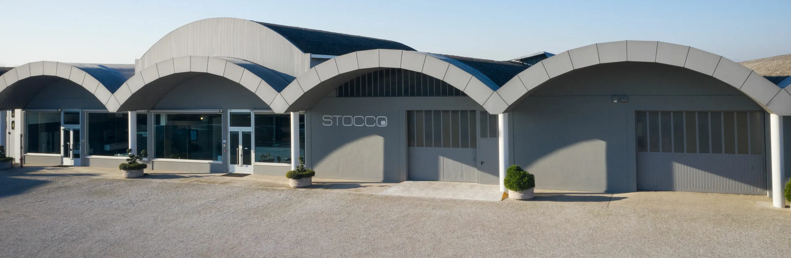 Außenansicht des Firmengebäudes von Stocco mit markanter gewölbter Dacharchitektur und großem Eingangsbereich.