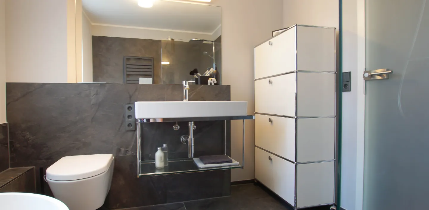 WC, offener Waschtisch und USM-Regal im modernen Bad vom Handwerksunternehmen bad & heizung Laabs in Potsdam.