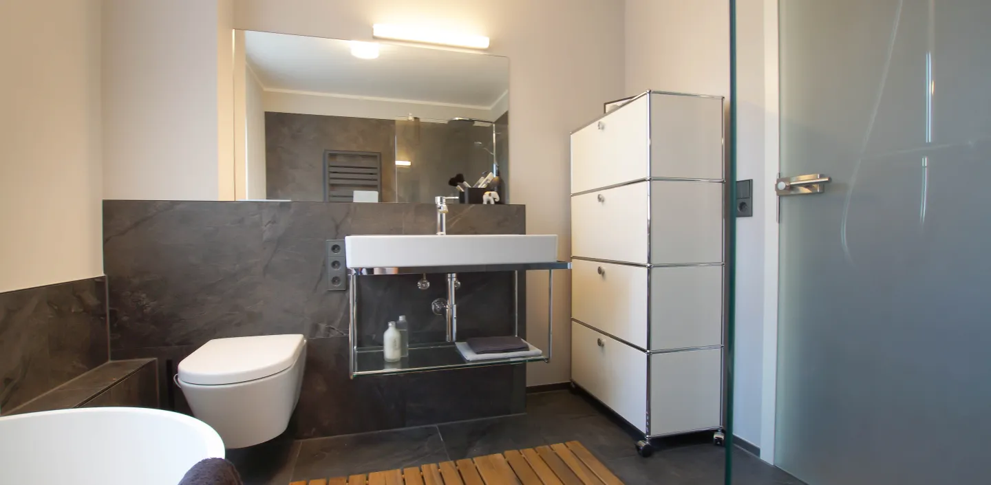 WC, offener Waschtisch und USM-Regal im modernen Bad vom Handwerksunternehmen bad & heizung Laabs in Potsdam.