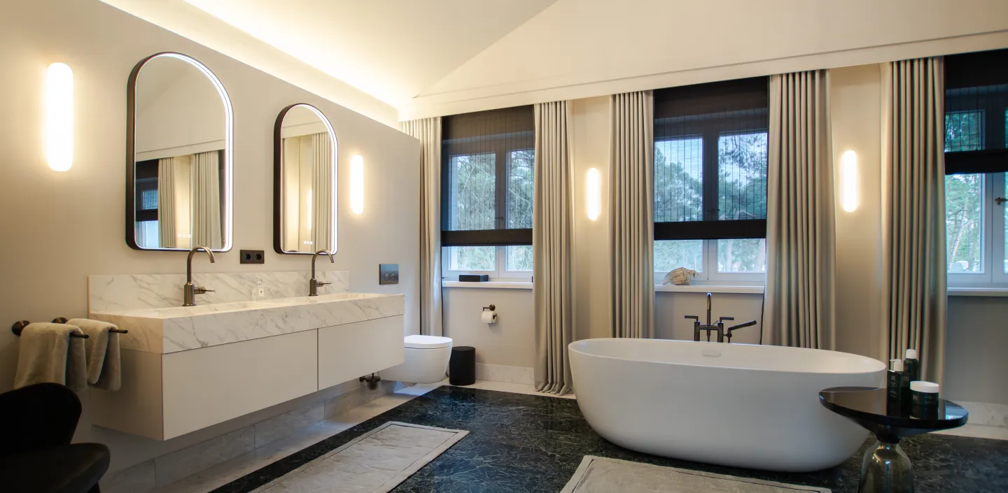 Großzügiges Badezimmer mit freistehender Badewanne und Doppelwaschtisch in Mamoroptik.