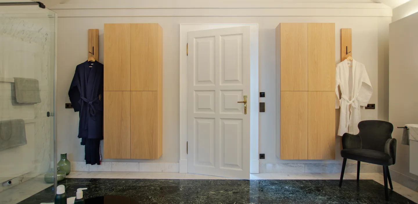 Badezimmer mit grünem Marmorboden und Echtholzschränken an den Wänden.