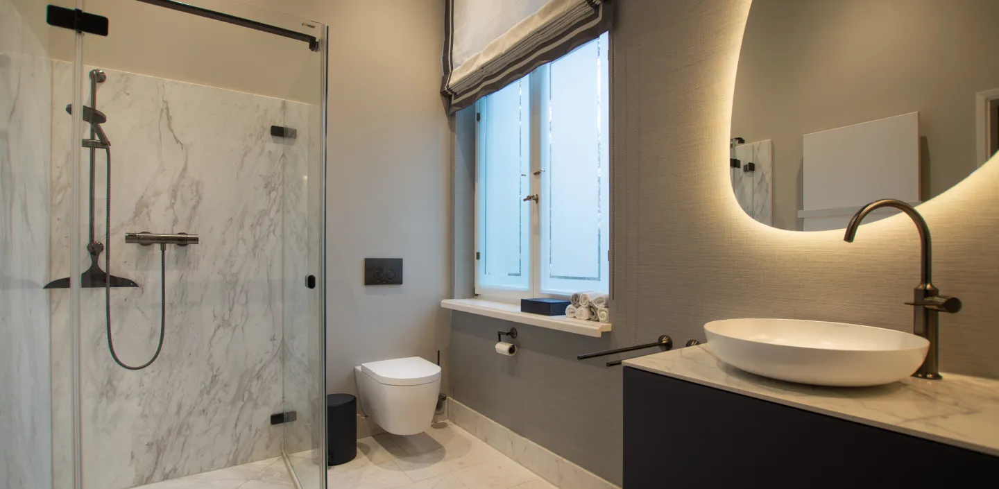 Zeitloses Gästebad mit Marmor-Dusche und grünem Marmor Boden, sowie Waschtisch mit Aufsatzschale.