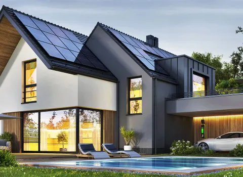 Das Bild zeigt ein energieeffizientes Einfamilienhaus mit Solaranlage, Elektroauto-Ladestation und einem Pool im gepflegten Garten.