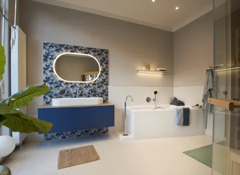 Blick in ein Badezimmer ausgestattet mit einer Laufen Doppelwaschtischanlage in blau und einer Mauersberger Eckbadewanne.