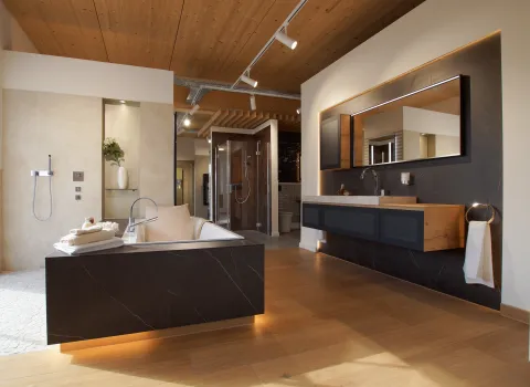 Komplettbad mit großzügiger Badewanne und indirekter Beleuchtung sowie großem Waschtisch mit Holz und Naturstein.