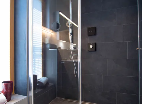 Dunkle Walk-in-Dusche mit Duschnische und Tür im Komplettbad vom Handwerksunternehmen bad & heizung Laabs in Potsdam.