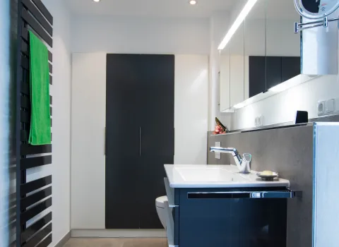 Breiter Einbauschrank mit weißen und grauen Türen im Komplettbad vom Handwerksunternehmen bad & heizung Laabs in Potsdam.