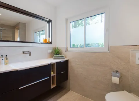 Sicht auf Waschtisch, Spiegel und Fenster eines Duschbads vom Handwerksunternehmen bad & heizung Laabs in Potsdam.