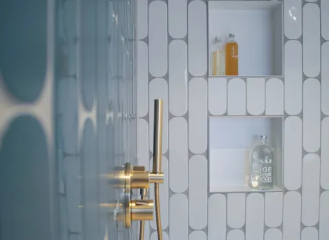 Goldene Duschen-Armatur und Duschnische im farbigen Bad mit blauen Fliesen vom Handwerksunternehmen bad & heizung Laabs in Potsdam.