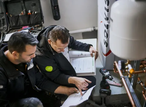 Zwei Anlagenmechaniker für Heizung arbeiten gemeinsam an der Installation einer modernen Heizungsanlage.