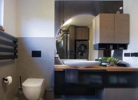 WC und Waschtisch mit großem, runden Spiegel in einem zeitlosen Bad vom Handwerksunternehmen bad & heizung Laabs in Potsdam.