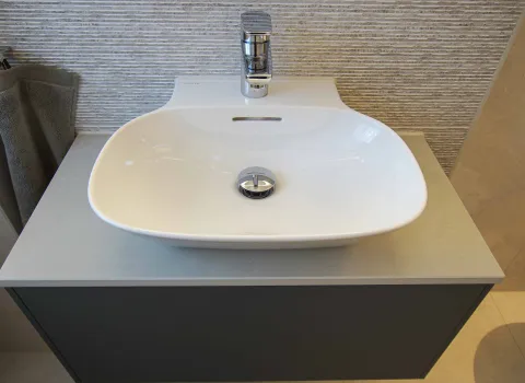 Waschtisch-Aufsatzschale INO mit Hahnlochbank auf einem grauen Waschtischschrank.