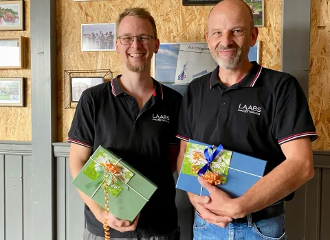 Zwei Mitarbeiter, die Geschenke in der Hand haben.