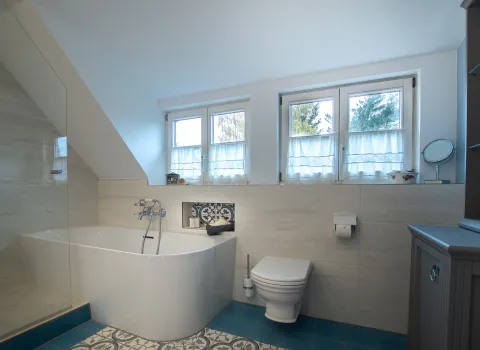 Loop & Friends Badewanne von V&B und WC in einem Badezimmer mit viel Fensterfläche.