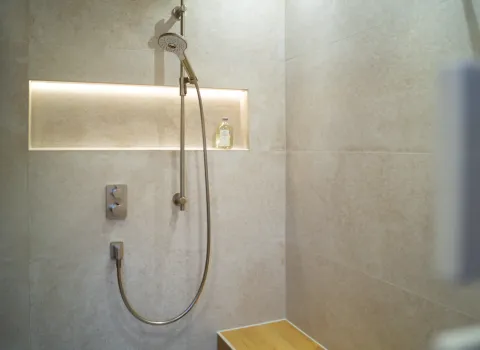 Walkin Dusche mit Handbrause und Nische für Shampoo. 