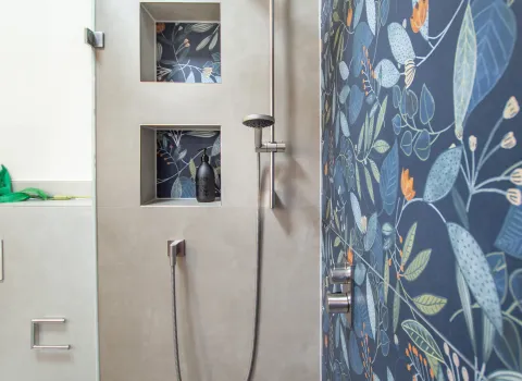 Moderne Dusche mit großer Regenbrause, integrierten Wandnischen und floral gemusterter Duschwand in Blau.