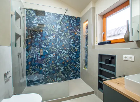 Referenzbad mit Duschbereich mit Regenkopfbrause und bunten, floralen Fliesen.