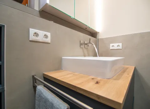 Waschtisch mit einer Wandarmatur in Edelstahl gebürtet mit einem Hebel, aus der Wasser läuft.