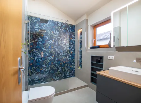 Badezimmer in grau und blau, mit großem Duschbereich mit floraler Fliese.