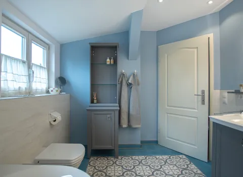 Blaues Badezimmer mit einem grauen Hochschrank und WC. 