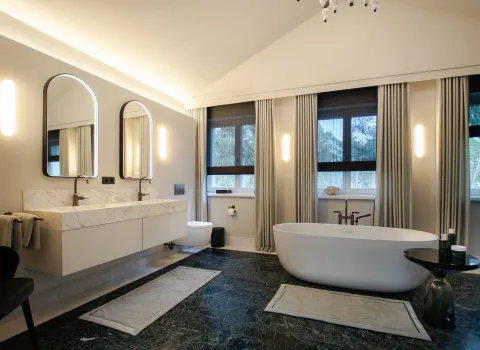 Großzügiges Badezimmer mit freistehender Badewanne und Doppelwaschtisch in Mamoroptik.