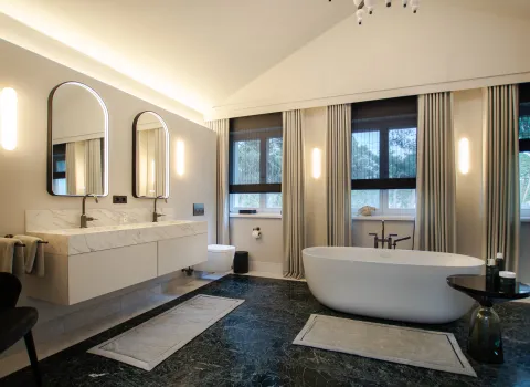 Großzügiges Badezimmer mit freistehender Badewanne und Doppelwaschtisch in Mamoroptik.