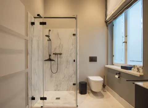 Gästebad mit Dusche in zeitlosem Design mit Marmorverkleidung und Artweger Duschabtrennung.