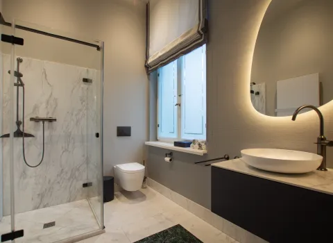 Zeitloses Gästebad mit Marmor-Dusche und grünem Marmor Boden, sowie Waschtisch mit Aufsatzschale.