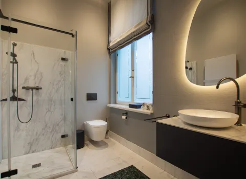 Zeitloses Gästebad mit Marmor-Dusche und grünem Marmor Boden, sowie Waschtisch mit Aufsatzschale.