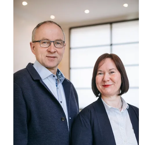 Das Geschäftsführer-Ehepaar der Firma Laabs bad und heizung steht in einem modernen Büro mit großen Fenstern und warmem Licht.