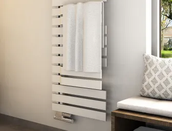 Asymmetrischer Handtuchheizkörper in einem hellen Badezimmer. Ein Handtuch hängt an den breiten Streben, daneben ein Fenster mit gemütlicher Sitzbank.