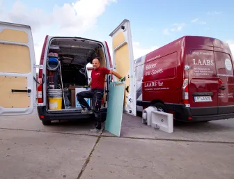 Ein Monteur lädt Material in seinen Transporter.