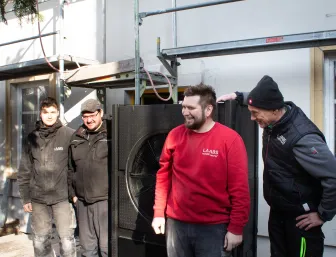 Elektro Team im Vordergrund einer Baustelle mit Wärmepumpe.