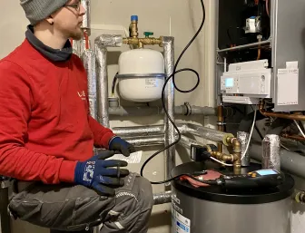 Ein Kundendienstmonteur steht vor einer Heizungsanlage und misst gerade den CO2 Wert.