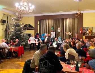 Großer Saal mit Tannenbaum und Bühne, sowie DJ, Weihnachtsfeier.