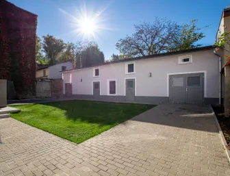 Remise mit gepfflasterter Einfahrt und Grünfläche davor.