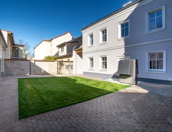 Gepflasterter Hof mit Grünfläche eines Zweifamilienhauses.