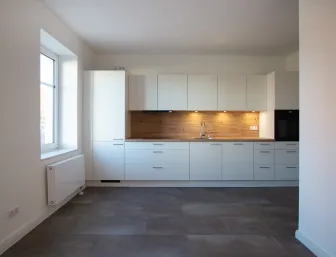 Küche mit weißer Front und Beleuchtung oberhalb der Arbeitsplatte.