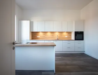 Küche mit weißen Fronten und Kochinsel. 