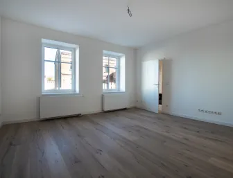 Leeres Wohnzimmer mit zwei Fenstern und Eichenparkett. 