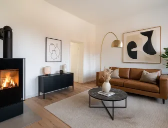 Eingerichtetes Wohnzimmer mit Kaminofen und Ledercouch.