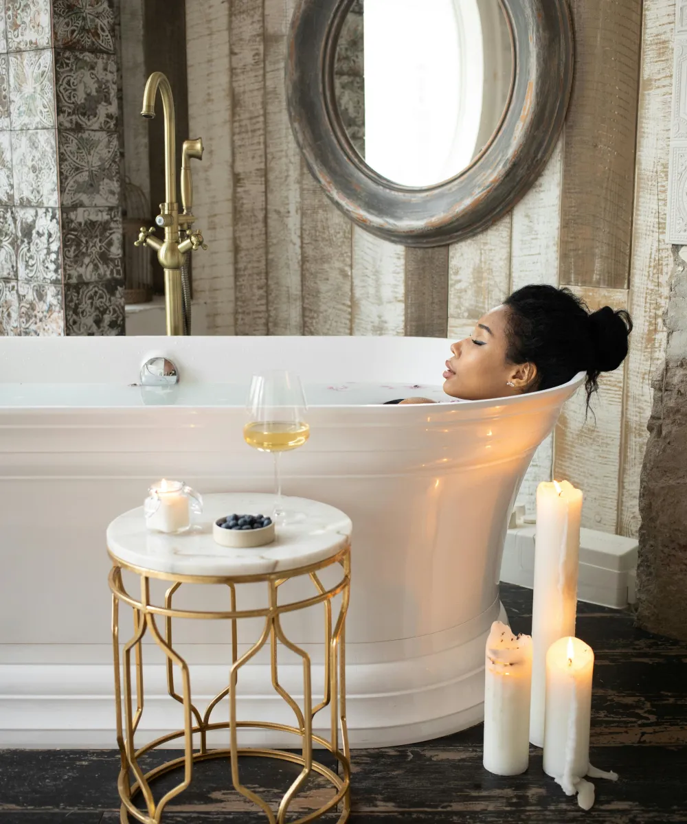 Eine Frau liegt in der Wanne und genießt die Auszeit mit einem Glas Wein und Kerzenschein.