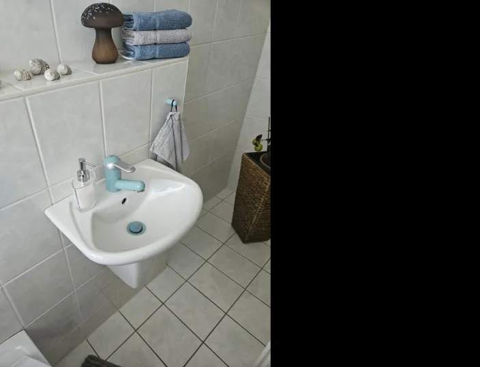 Altes Gästebad mit weißen Fliesen und hellblauer Armatur. 