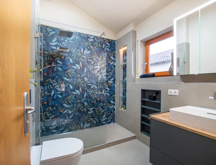 Badezimmer in grau und blau, mit großem Duschbereich mit floraler Fliese.