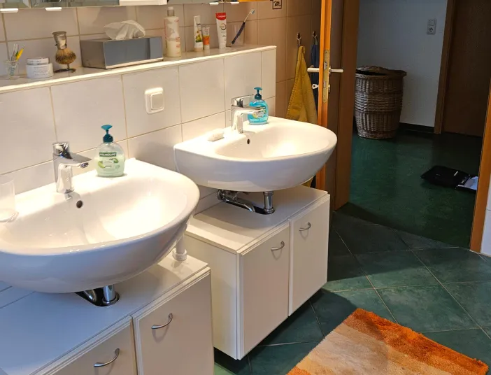 Altes Badezimmer mit Doppelwaschtischanlage in weiß - Ausgangssituation vom farbigen Duschbad.