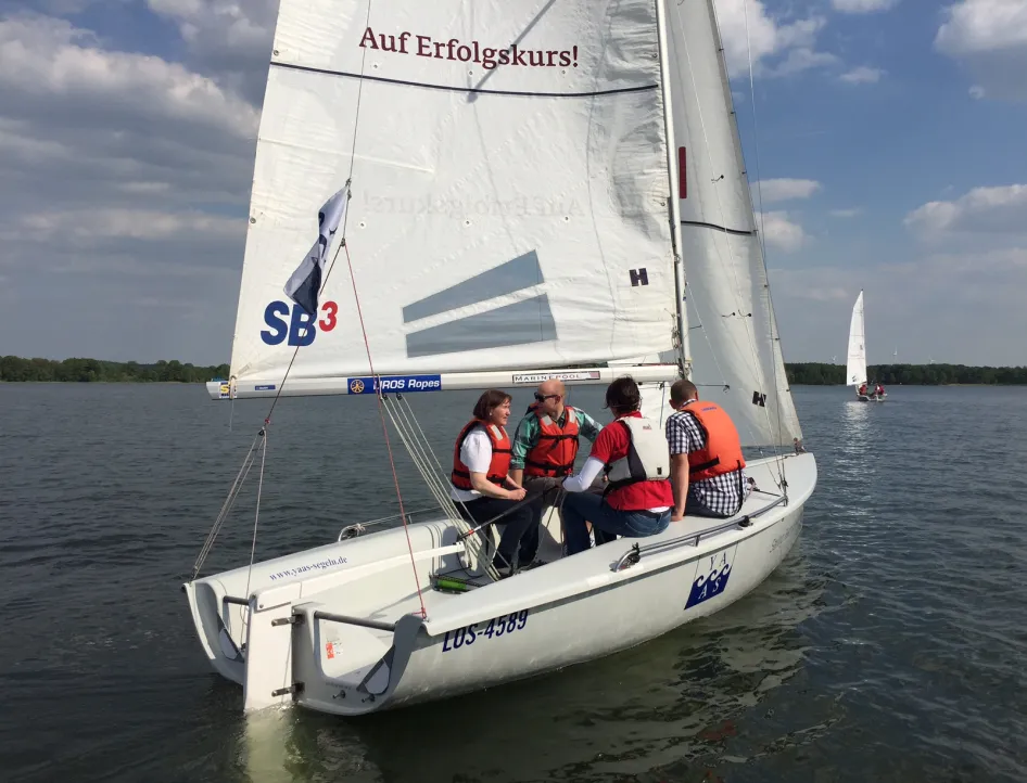 Vier Personen der Firma Laabs sitzen in einer fahrenden Segelboot.